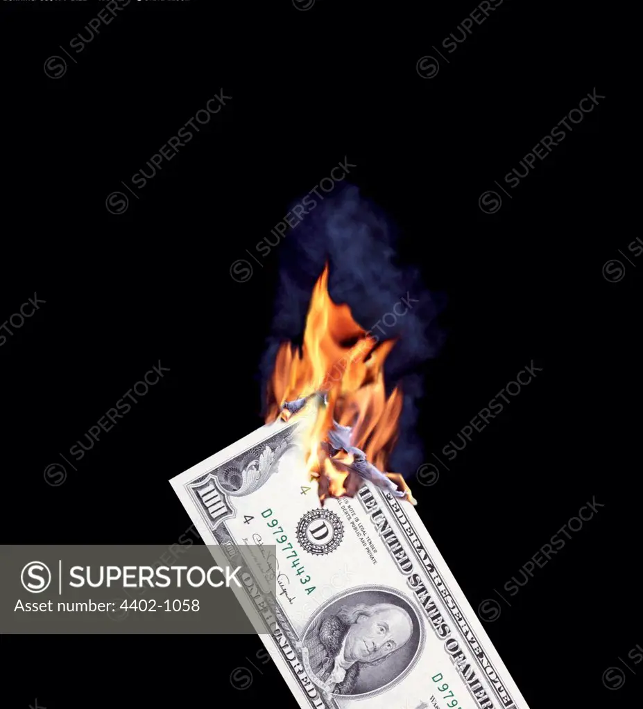 Hand holding burning $100 bill