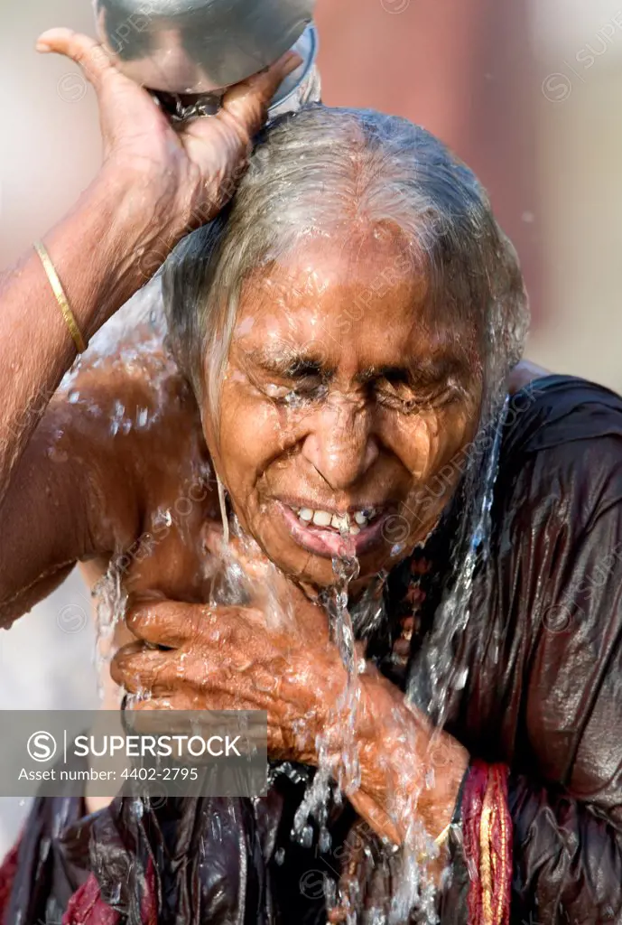 Hindu woman pouring water over her head in the Ganges, Varanasi, India