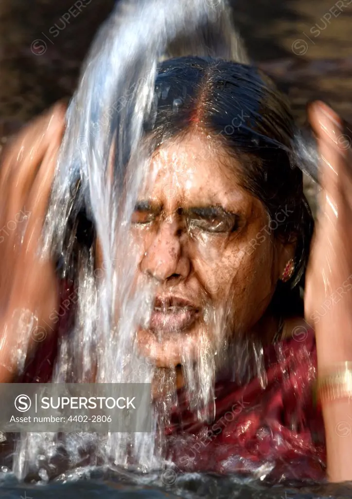 Hindu woman immersing herself in the holy waters of the Ganges river, Varanasi, India