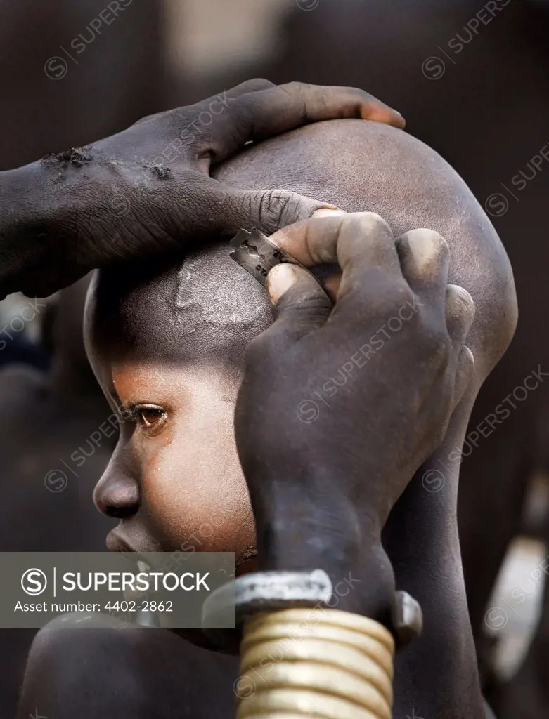 Karo child having his head shaved, Omo delta, Ethiopia, Africa