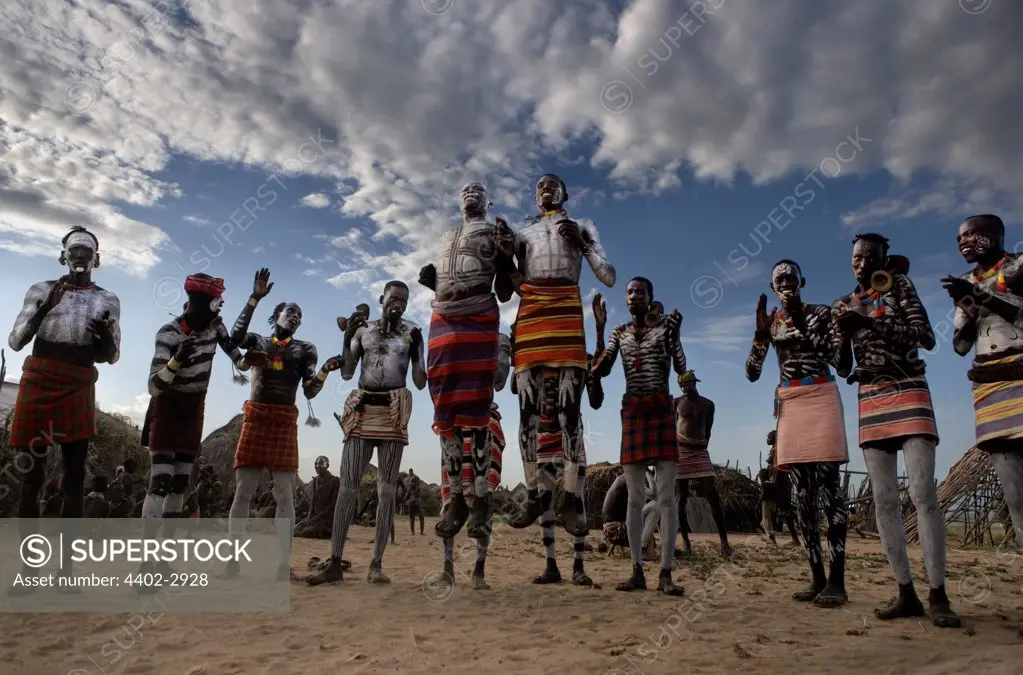 Karo tribesman dancing in the circle, both with feet off the ground, Omo Delta, Ethiopia, Africa.
