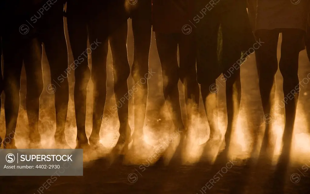 Close up of the legs of Dassenech children, backlit, dancing at sunset, Omo Delta, Ethiopia, Africa.