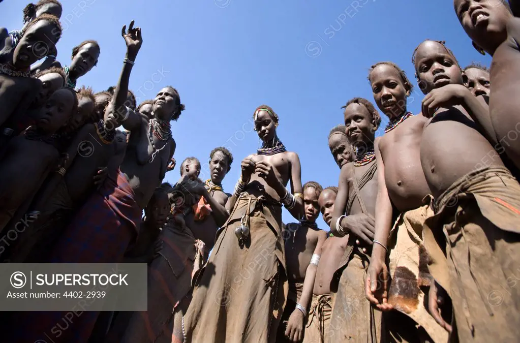 Circle of Dassenech tribespeople looking down curiously at camera. Omo Delta, Ethiopia, Africa.