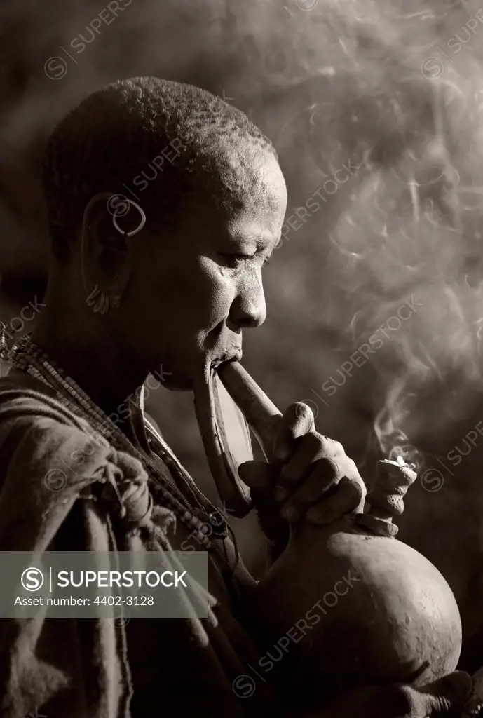 Suri tribeswoman with clay lip plate, smoking, Omo Delta, Ethiopia