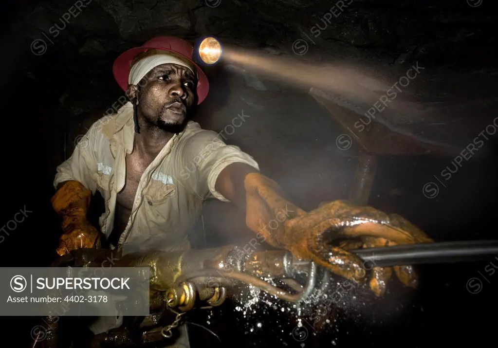 Gold miner at work drilling underground rock face, near Johannesburg, South Africa
