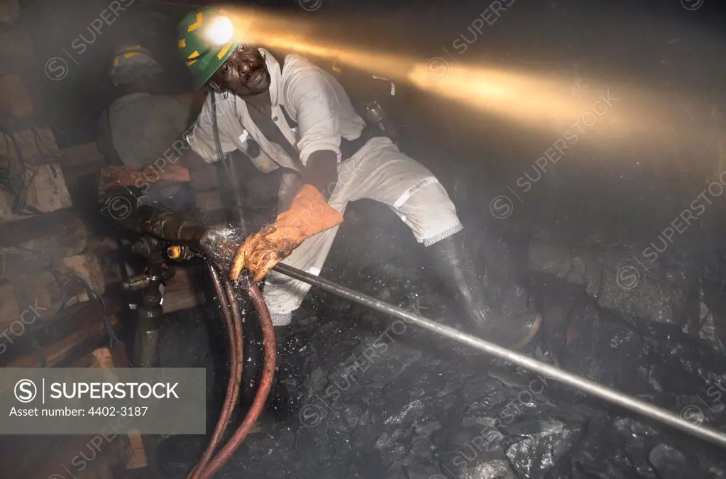 Gold miner at work drilling underground rock face, near Johannesburg, South Africa