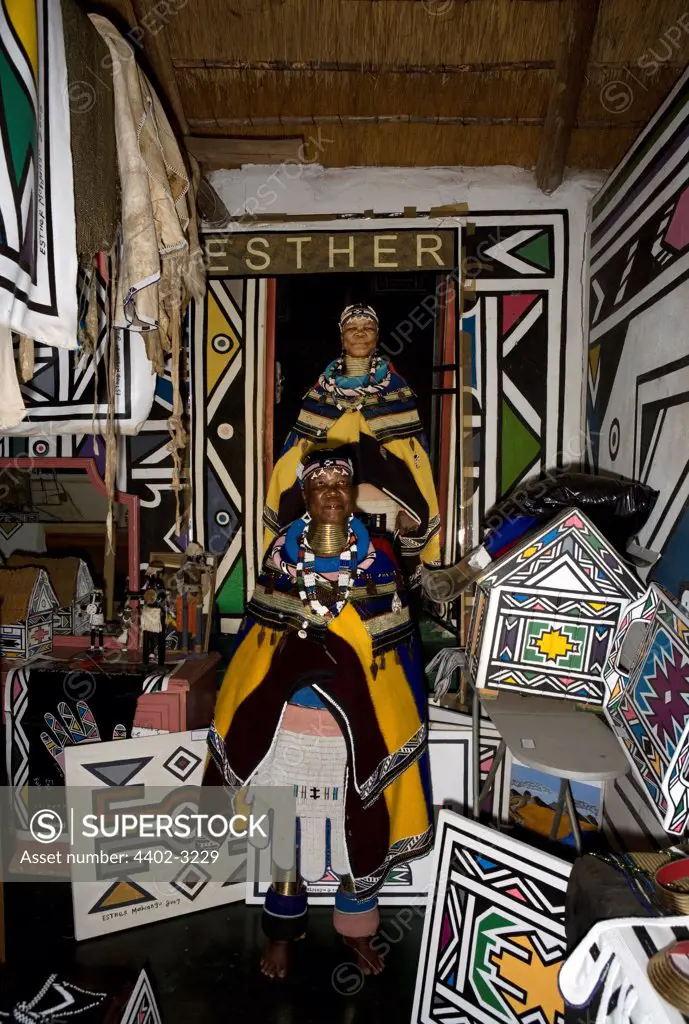Ndebele artist, Esther Mahlangu, standing beneath a photograph of herself, South Africa.