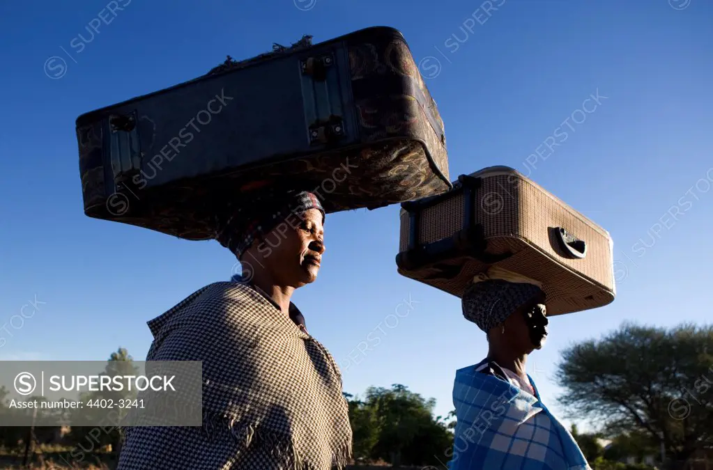 Ndebele women carrying suitcases balanced on their heads, South Africa