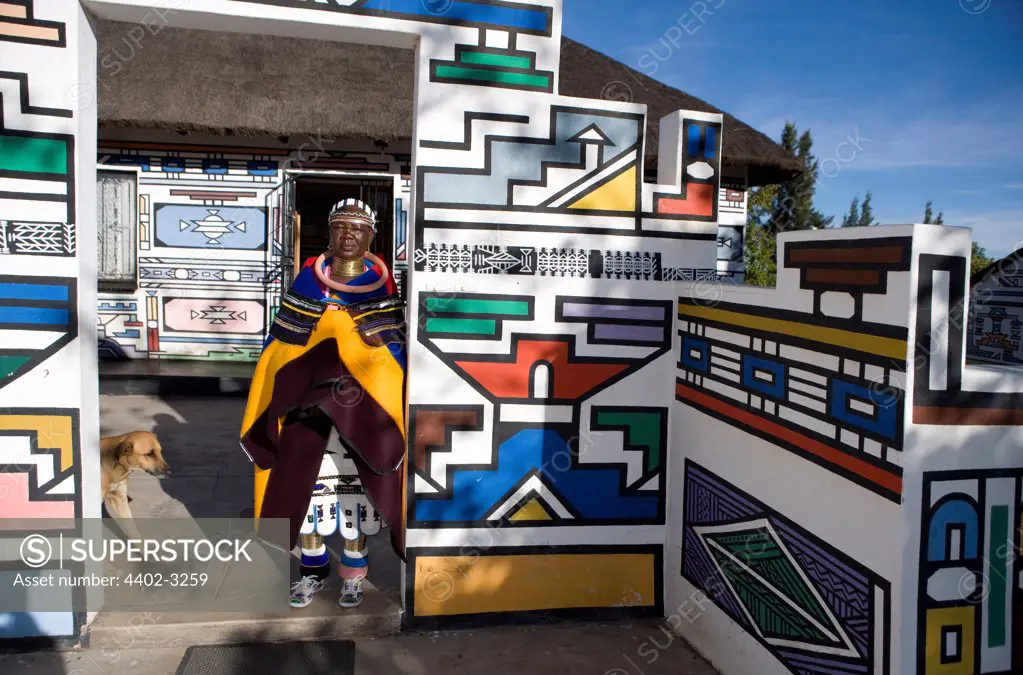 Ndebele woman outside her traditionally decorated house, South Africa