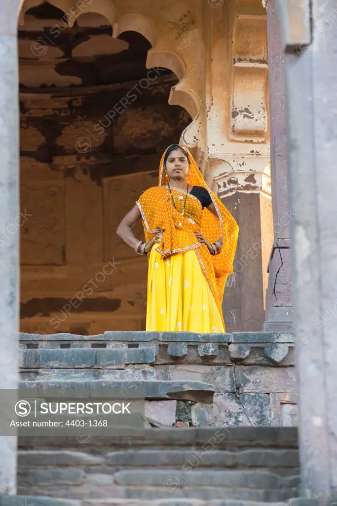 Rajasthani Woman in traditional dress standing in sunlit opening of old building Ranthambhore Rajasthan India