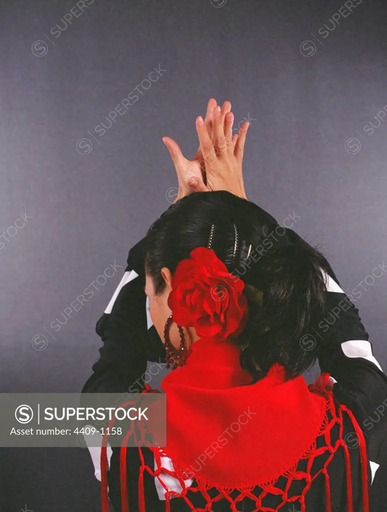 Flamenco dancer with back turned, clapping her hands.
