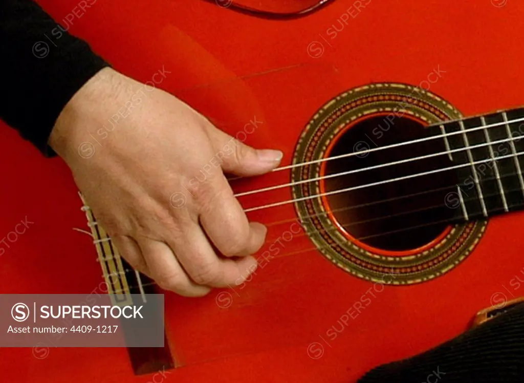 Detail of hand playing a flamenco guitar.