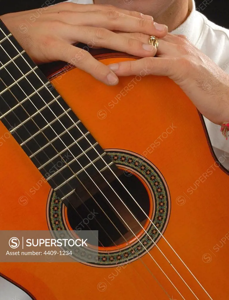 Hands and flamenco guitar photo detail.