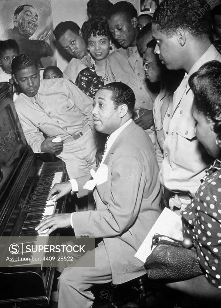 American jazz musician Duke Ellington plays the piano for a group of servicemen and women, Hartford, Connecticut, 1942. Jazz vocalist Joya Sherrill, who sang with Ellington thorughout most of the 1940s, stands at center rear (she wears a pearl neckace). A poster de Ellington is on the wall.