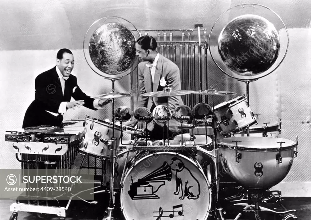 Duke Ellington and Sonny Greer posed by 1930s drum kit.