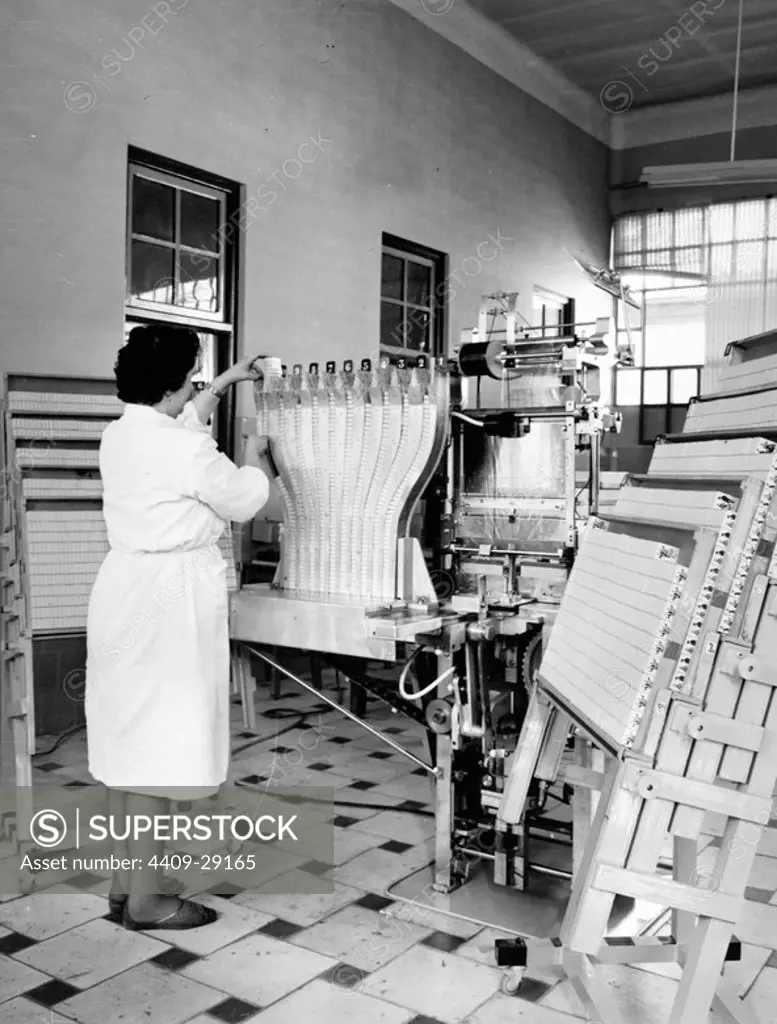 Trabajadora con una máquina para empaquetar cajas de cerillas. Años 50.