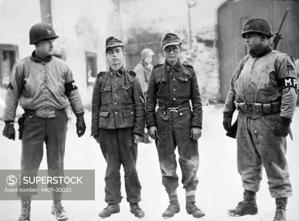 Dos soldados norteamericanos custodian a dos jóvenes prisioneros alemanes capturados en la eliminación del saliente de Bastoña.