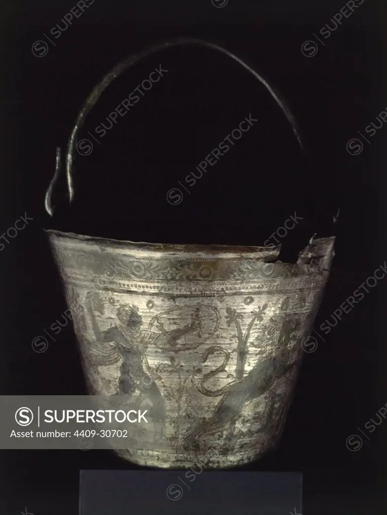 Sítula de una sola lámina de bronce doblada, decorada con una escena de caza. Sobre la decoración vegetal, baño de plata. Bueña, Teruel. S. V-VI d. C. Altura: 15,5 cm. Diámetro base: 13 cm. Diámetro boca: 23,5 cm. Museum: MUSEO ARQUEOLOGICO, MADRID, SPAIN.