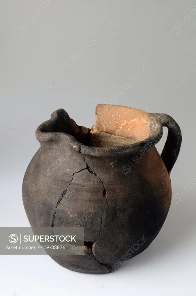 Common ceramic jug with flat base , spout , mouth lobed , globular body with signs showing the action of fire. Height 105 mm Width 127 mm mouth diameter 105 mm diameter base 84 mm (6 th- 7 th Ce ) - Visigoth period belonging of the " Burgo de Santiuste Museum" in Alcalá de Henares. (Madrid). SPAIN.