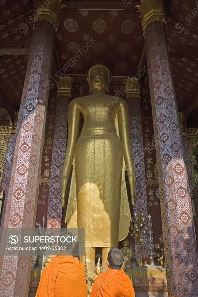 MONJES BUDISTAS frente a una estatua en el TEMPLO DE WAT SOP. LUANG PRABANG (Patrimonio de la Humanidad). Laos.