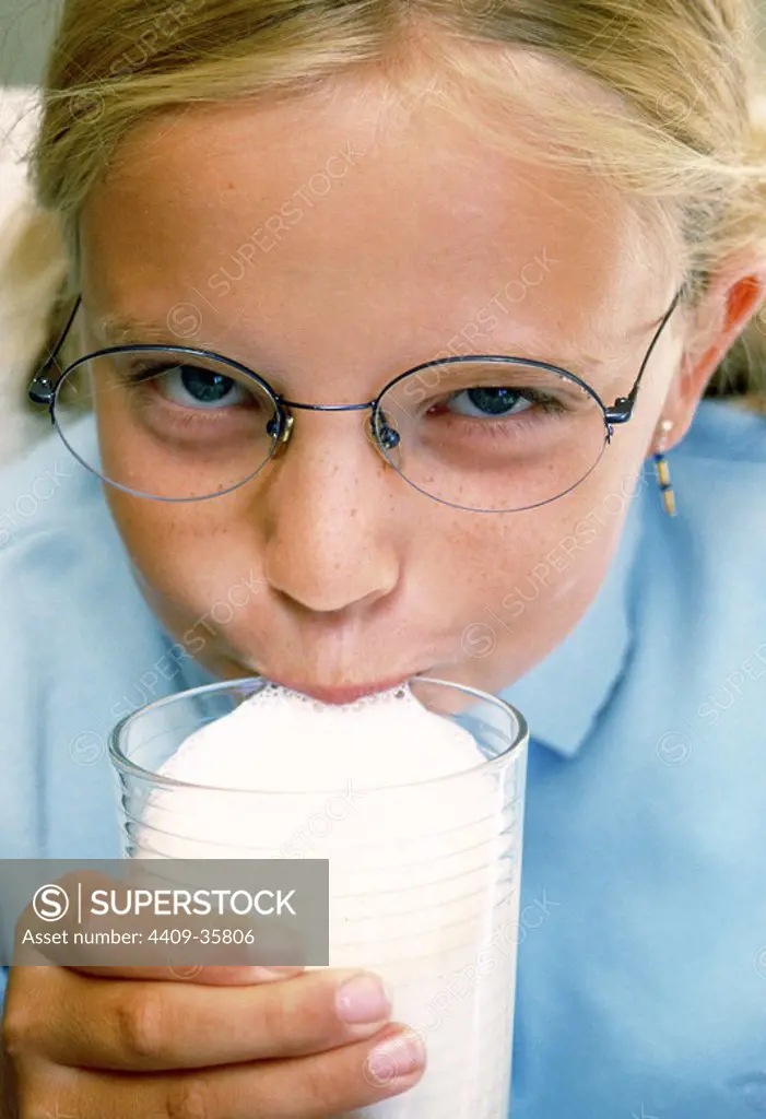 Niña de 10 años bebiendo un vaso de leche.