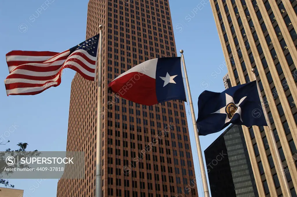 United States of America, State of Texas, Houston. Downtown. Flags of the United States, the State of Texas and the city of Houston. In the background, view of the TC Energy Center, formerly known as Bank of America Center. Postmodern skyscraper completed in 1983. It was designed by architects Philip Johnson and John Burgee.