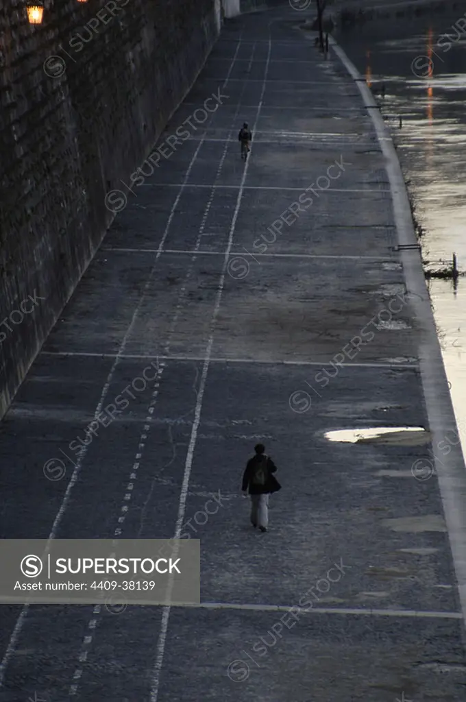 Italy. Rome. People walking along a promenade on the banks of the river Tiber.