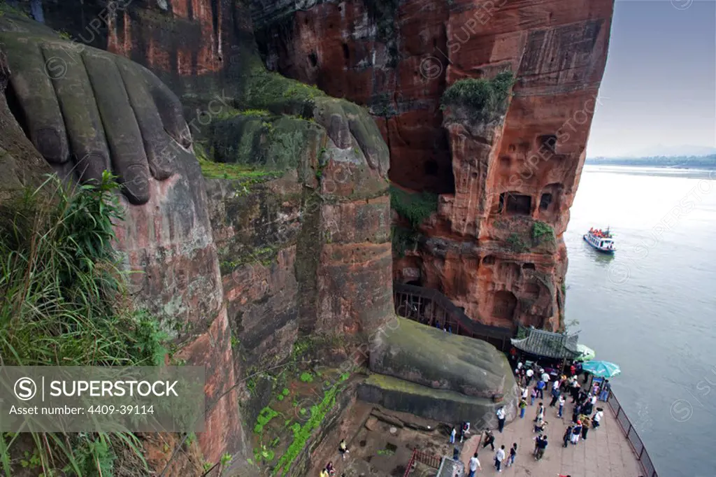 Tourist visiting Leshan Giant Buddha (713-803). Carved into a cliff of Mount Lingyun. Sichuan Province. China.