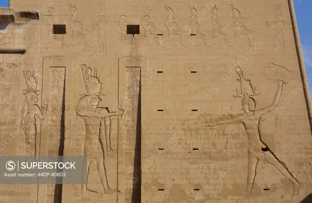 Temple of Horus. The pharaoh Ptolemy XII Neo Dionysos sacrificing prisoners to the god Horus and goddess Hahtor. Main entrance. First pylon. Detail. Edfu. Egypt.