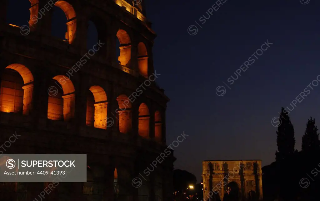 Italy. Rome. The Colosseum (Coliseum) or Flavian Amphitheatre. Elliptical construction built of concrete and stone. 1st century A.C. Nocturnal view. At the background, the Arch of Constantine.
