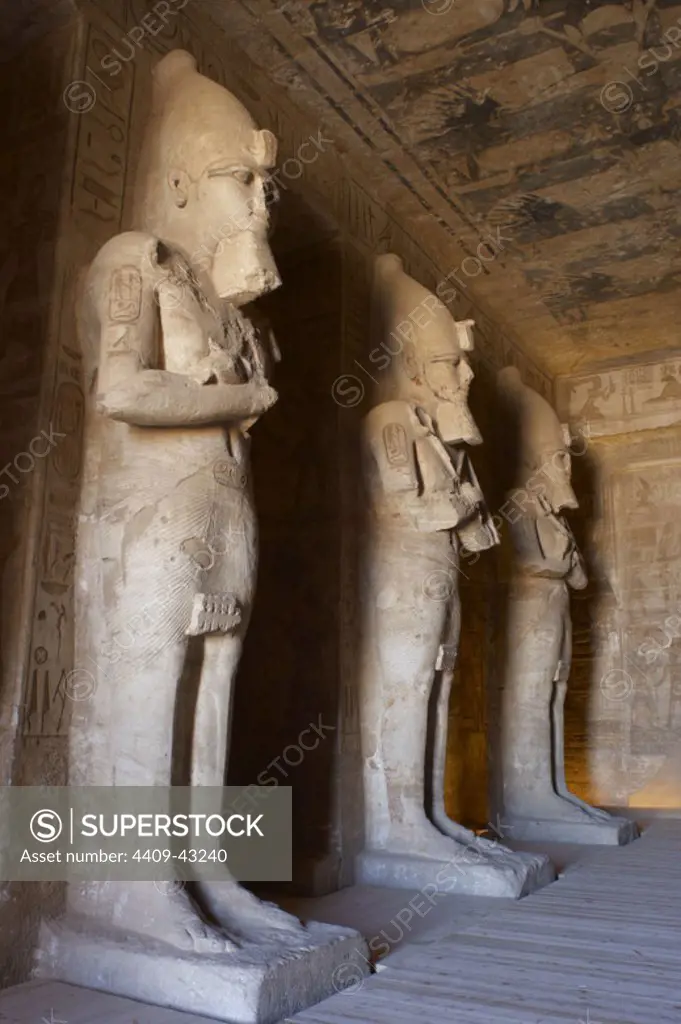 Egyptian art. Great Temple of Ramses II (1290-1224 BC). Funerary temple carved in the rock. View from inside the first room, with three of the eight statues of Ramses II as the god Osiris. Abu Simbel. Egypt.