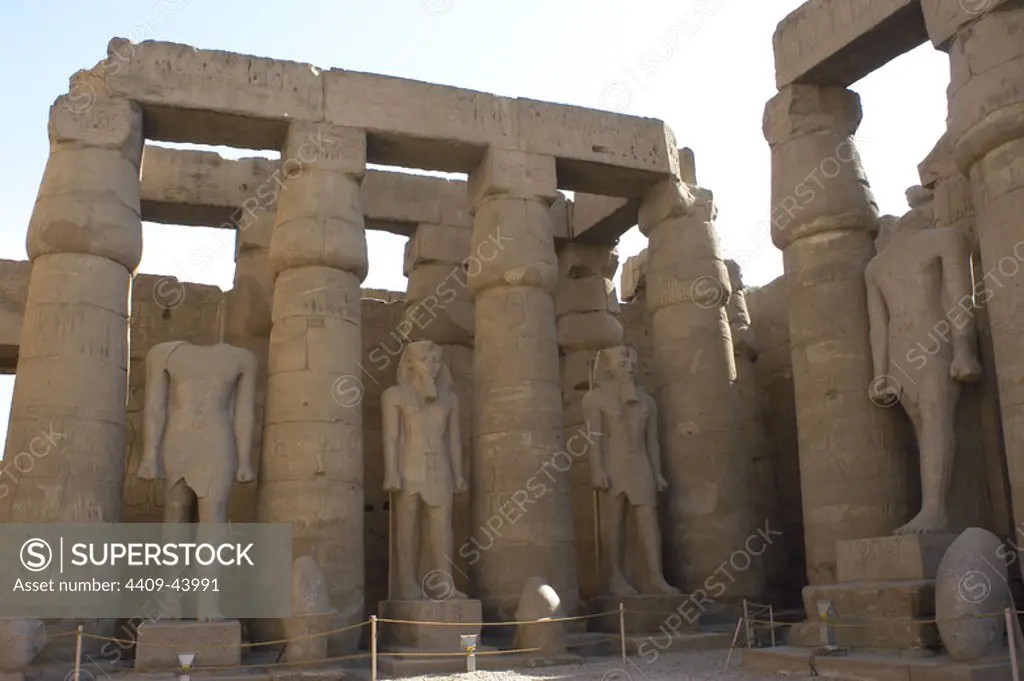 Temple of Luxor. First courtyard called the Ramses II surrounded with smooth shaft columns and closed papyrus capitals and decorated with statues of Ramses II. New Kingdom. Egypt.