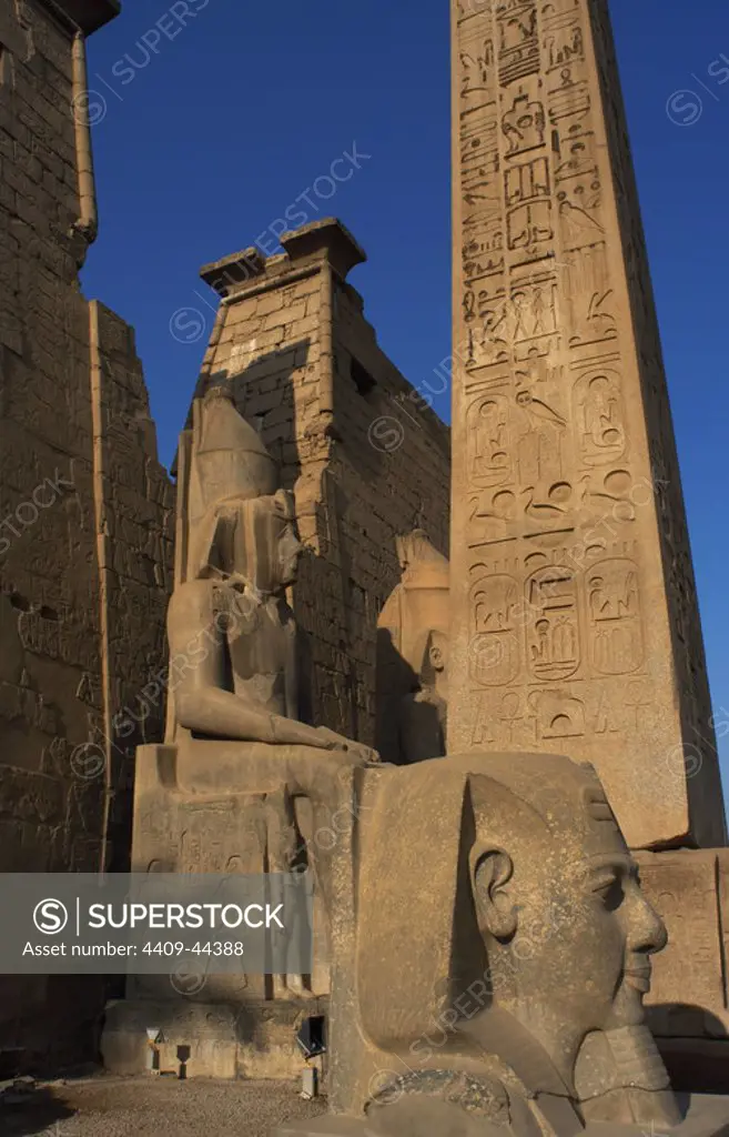 EGYPT. TEMPLE OF LUXOR. Partial view of the first pylon of the temple, the remains of an obelisk of pink granite, and head and colossal statues of Ramses II. Ancient Thebes "Waset,.