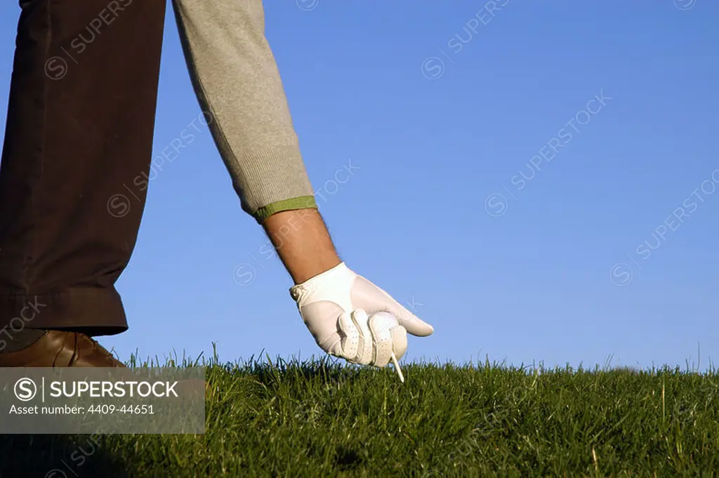 Golfer picking up the ball.