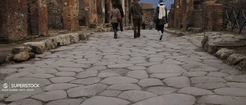 Italy. Pompeii. Tourists walking by the cobbled street.