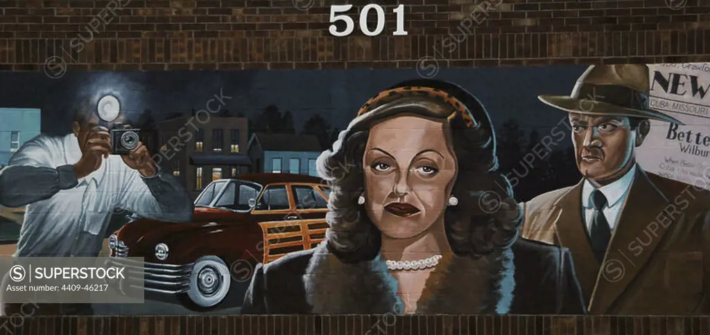 Bette Davis (1908-1989). American film actress, winner of two Oscars. Mural depicting the visit of Bette Davis and her husband to the town of Cuba (Missouri). Bette Davis stayed at the Southern Hotel. A photographer took a picture of them against their will and was chased by Davis' husband. He escaped and the photo appeared in the press. By Ray Harvey (1926-2011). Series of murals depicting historical scenes of both local and national themes. Cuba, State of Missouri, United States.