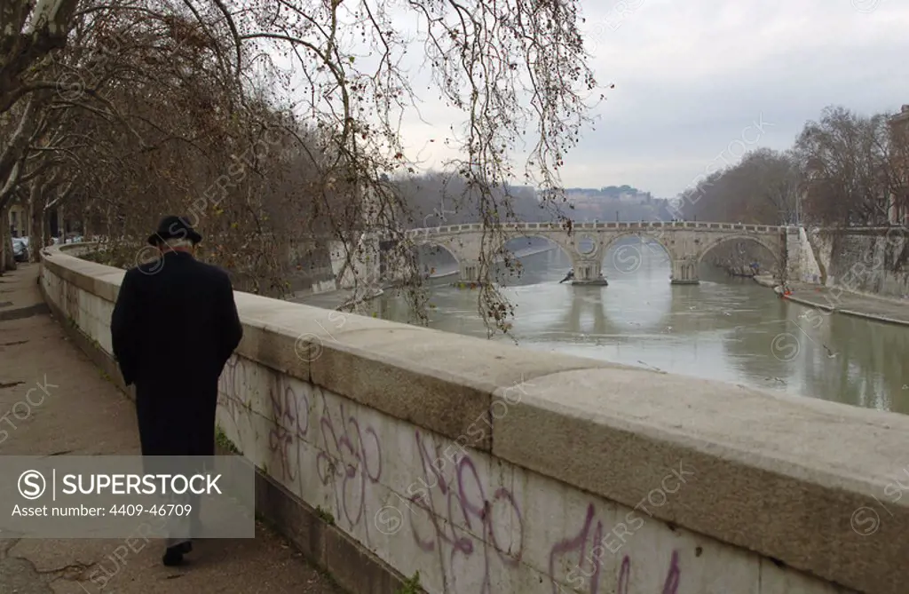 Italy. Rome. Old man walking along the river Tiber.