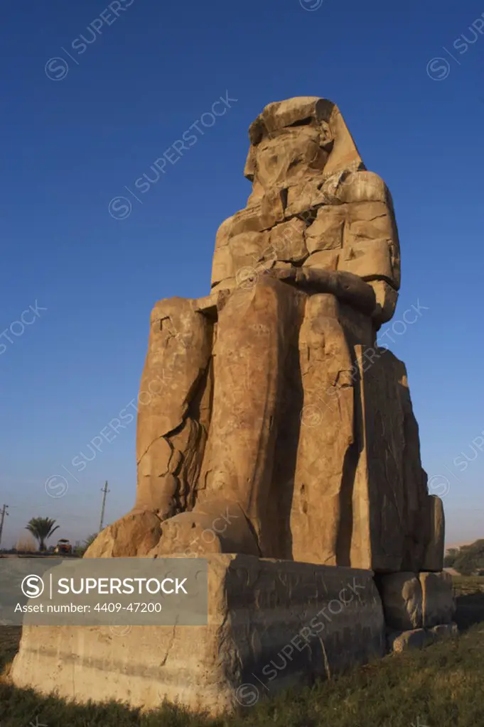 Colossi of Memnon. Stone statues depicting pharaoh Amenhotep III (14th century B.C.) in a seated position. Eastern colossus. Eighteenth Dynasty. New Kingdom. Luxor. Egypt.