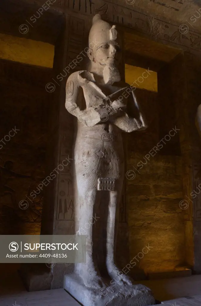 Egyptian art. Great Temple of Ramses II (1290-1224 BC). Funerary temple carved in the rock. View from inside the first room, with one of the eight statues of Ramses II as the god Osiris. Abu Simbel. Egypt.