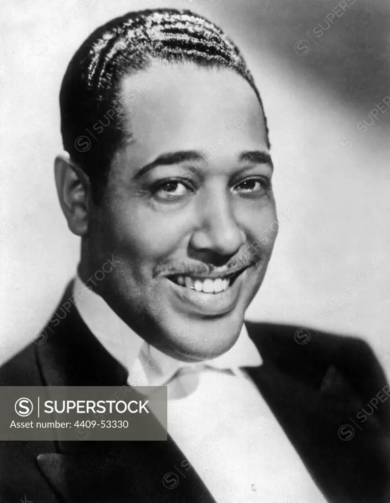 Headshot studio portrait of Amercian jazz pianist, composer and badleader Duke Ellington, wearing a tuxedo and a bow tie and smiling. 1937.