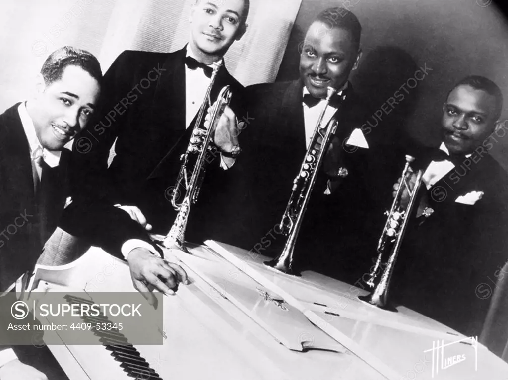 Portrait of American jazz musician Duke Ellington at a white piano with three of his horn players (L-R): Artie Whetsol, Cootie Williams and Rex Stewart. 1940.