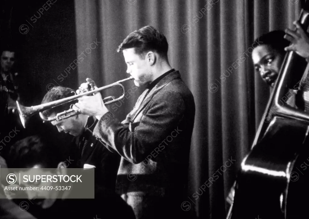 American jazz musician and singer Chet Baker playing trumpet on stage with a bass player and other musicians during a performance. 1954.