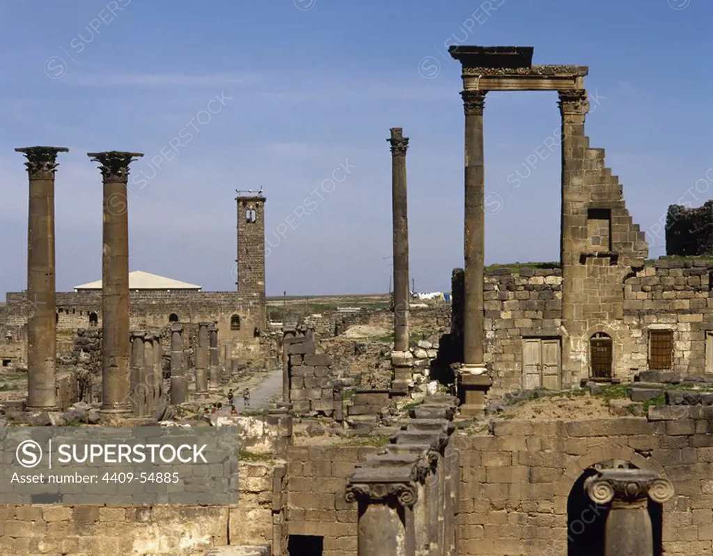 Syria, Bosra. Ancient Roman city. Ninfeo. Remains of the Corinthian capitals, 2nd century AD. In the background the mosque of Al-Omari. Photo taken before the Syrian civil war.
