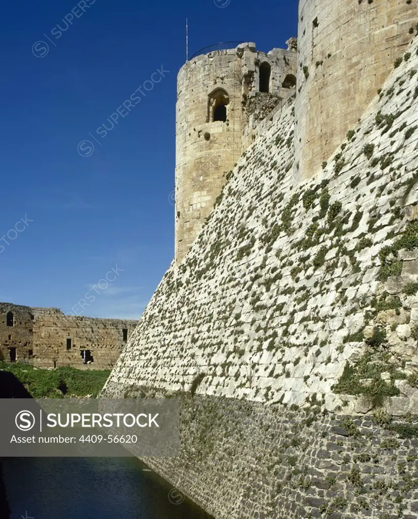 Syria Arab Republic. Talkalakh District. Krak des Chevaliers. Crusader castle, under control of Knights Hospitaller (1142-1271) during the Crusades to the Holy Land, fell into Arab control in the 13th century. View of walls and moat. Photo taken before Syrian Civil War.
