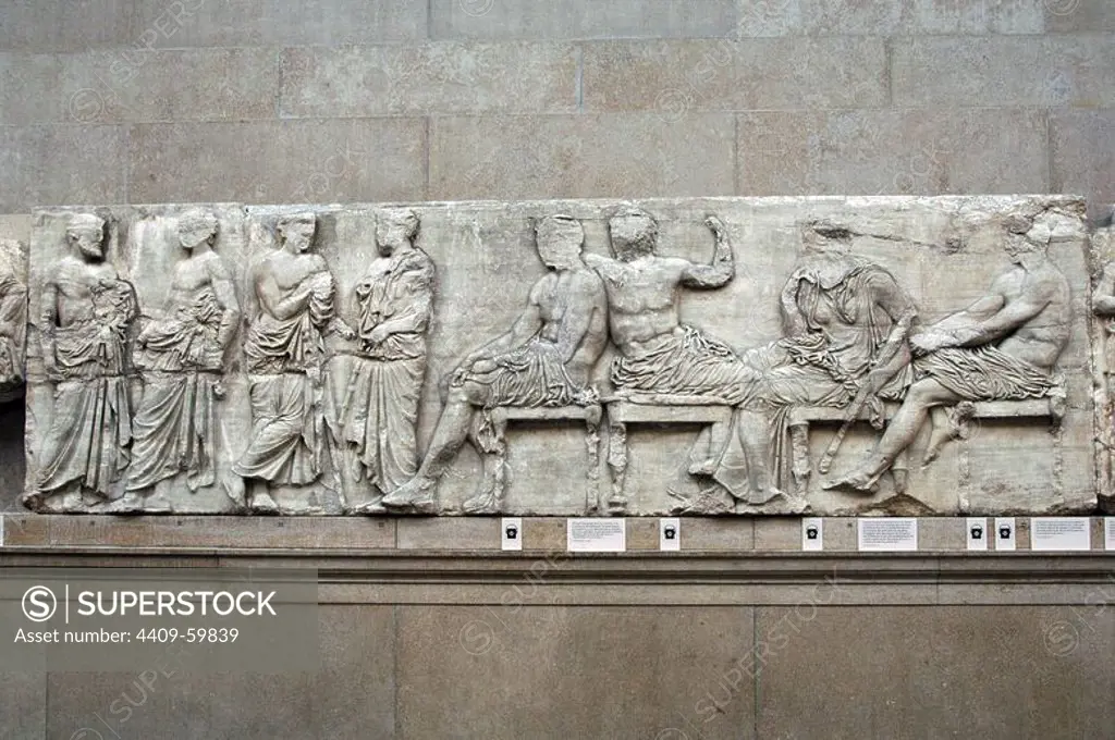 The Parthenon frieze. East side. 447-432BC. Greek Classical period. Part of the central section of the east frieze. Zeus and Hera seated next to a standing man receiving the folded peplos from a young boy. British Museum. London. England. United Kingdom.