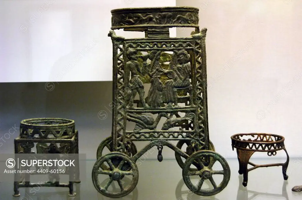 Wheeled stand for a vessel with an animal frieze on the ring. The scene depicts a seated figure playing a stringed instrument with another playing a similar instrument. Next to this figures, a server carries a jug in his right hand and a cup in his left. In the lower par, a water-bird attacks an a fish. 1225-1100 BC. Bronze. Made in Cyprus. British Museum. London. England. United Kingdom.