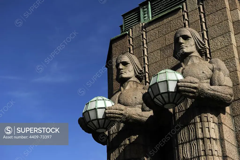 Finland. Helsinki. The torchbearer lamps. Two of the four monumental granite sculptures in Finnish romantic style, designed in 1904 by architect Gottlieb Eliel Saarinen (1873-1950) and built between 1910-1914, by sculptor Emil Wikstrom (1864-1942). They decorate the southern entrance to the Central Railway Station and hold balloons light up at night that represent the light of the world.