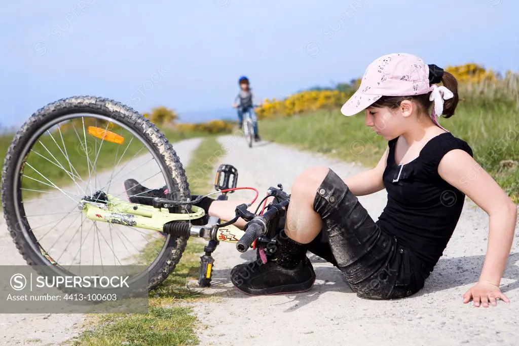 Young girl falling from a bike on a countryside path