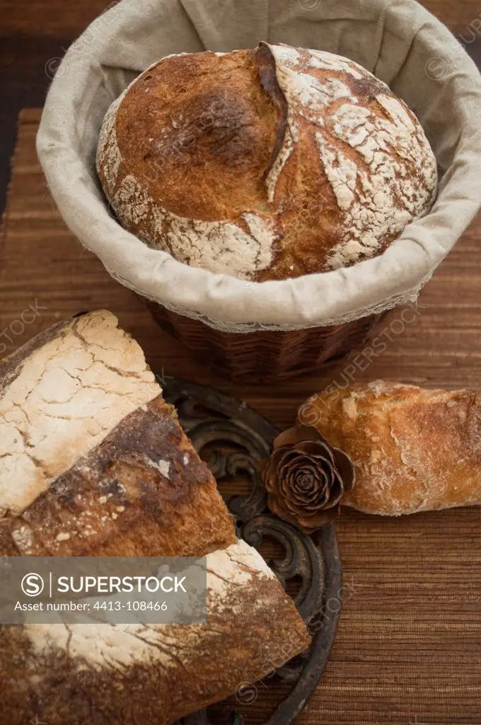 Loaf of bread in a bread basket and bread cut on table