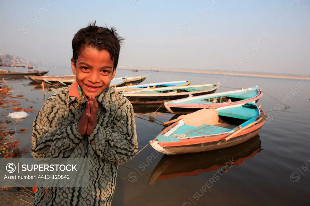Portrait of boy saluting and boats Varanasi India